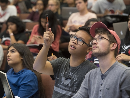 Students in a General Chemistry lecture hall point and discuss something on the screen in front of them
